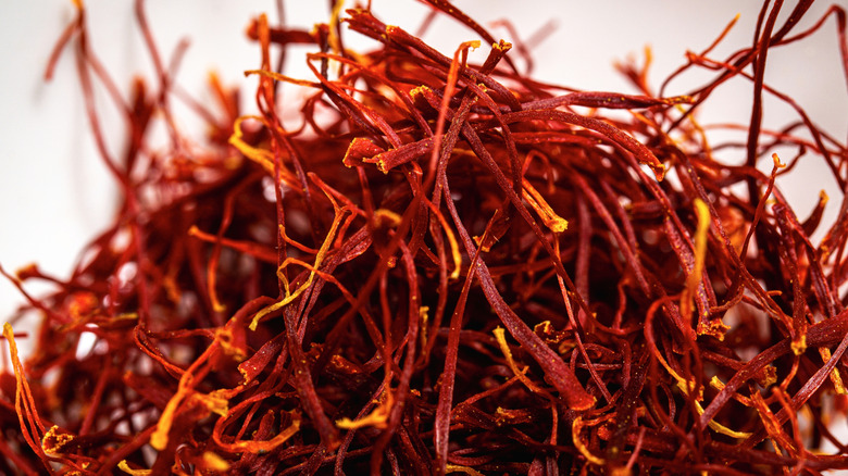 A pile of dark red and orange saffron stamens are shown close-up