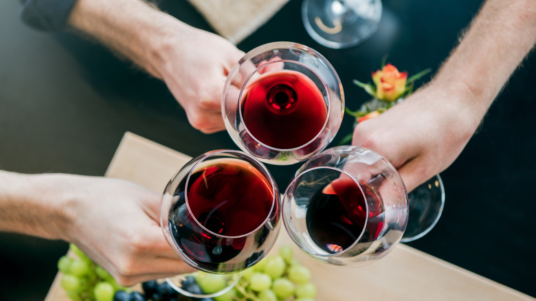 Birds eye view of three people doing a toast with red wine