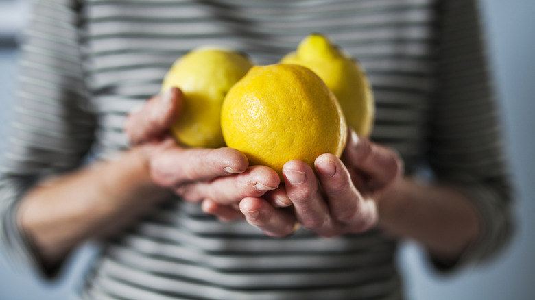 Hands holding three lemons