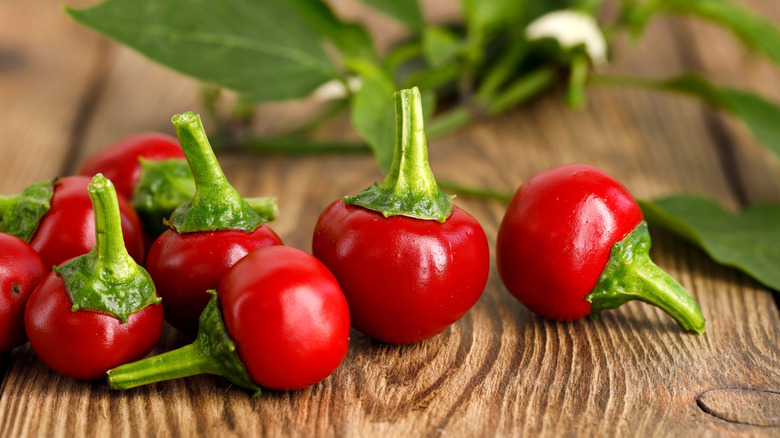 fresh red cherry peppers on a wooden cutting board