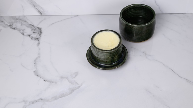 A black butter bell on a marble countertop