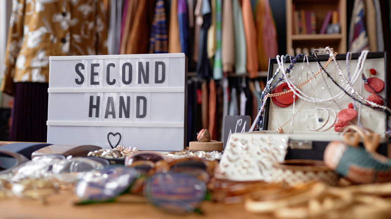 A sign reading "second hand" appears on a table at a thrift store.