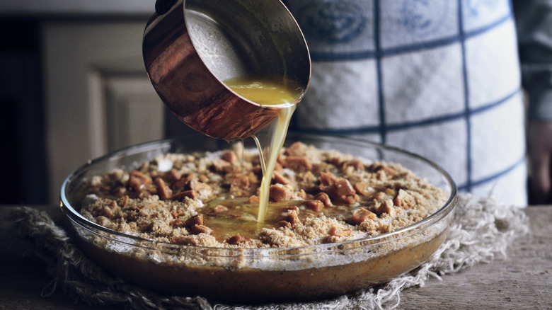Someone adding liquid to a dump cake