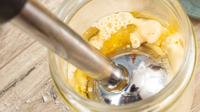 handblender inside jar of separated mayo with fresh cut lemon beside it
