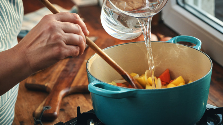 adding water to a pot with vegetables