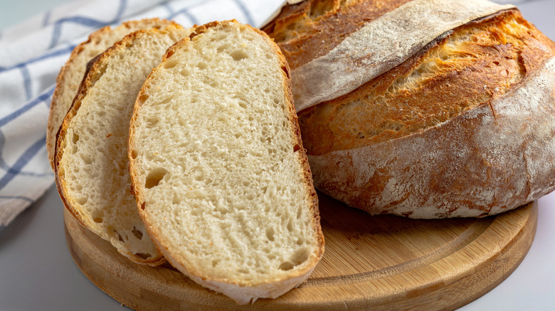 sourdough bread with a crispy crust and soft, airy interior, sliced and displayed on a wooden cutting board.