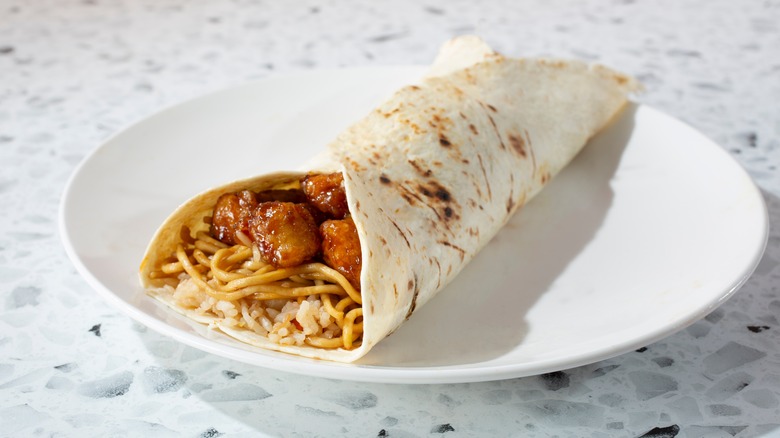 a burrito with orange chicken, rice, and chow mein noodles