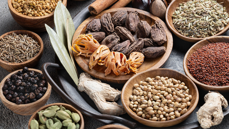 Array of whole spices in wooden bowls