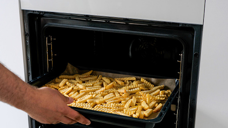 A tray of frozen French fries in the oven.