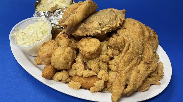 Various pieces of fried fish and hushpuppies stacked high on a plate.