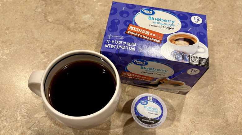 A mug of Great Value Blueberry coffee next to its box and a pod