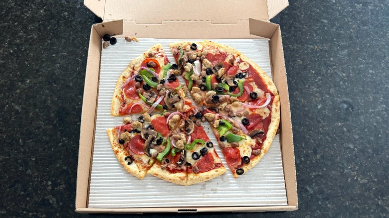 A box of Chuck E. Cheese supreme pizza on a black table