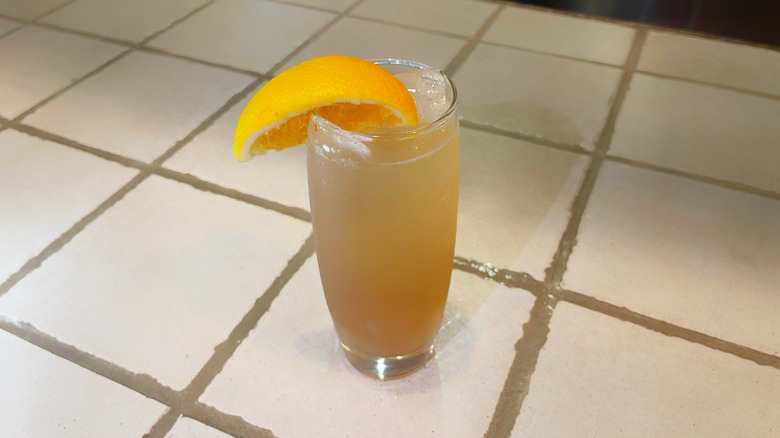 The Amaretto Sour from Olive Garden on a white bar top with an orange wedge garnish