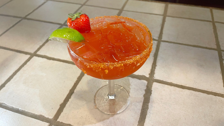 The Strawberry Limoncello Margarita from Olive Garden on a white bar top with a fresh strawberry and lime garnish