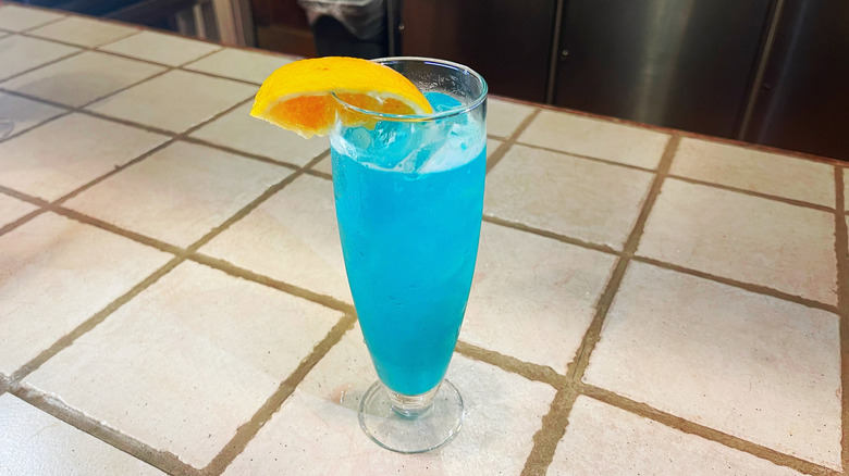 The Blue Capri from Olive Garden on a white bar top with an orange wedge garnish