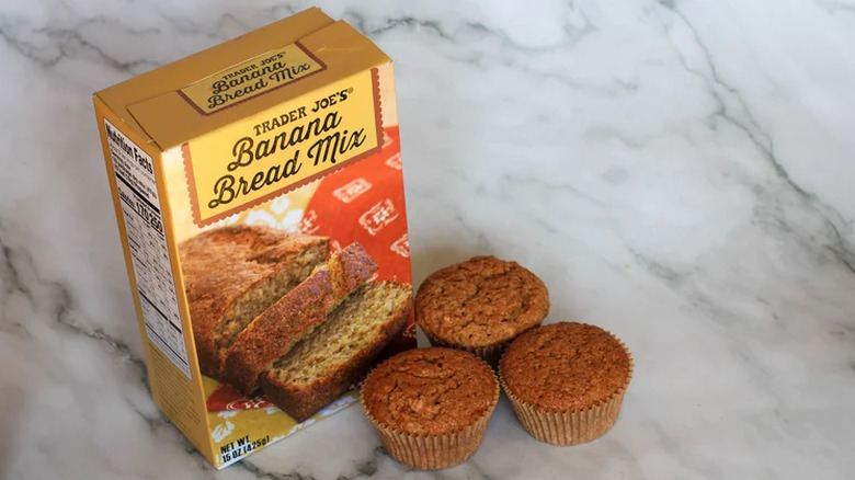 Trader Joe's banana bread mix with banana bread muffins on marble background