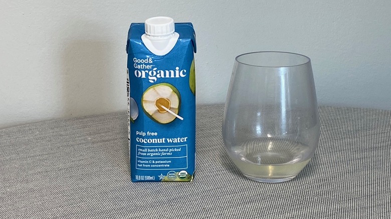 A carton of Good & Gather coconut water on a table beside a glass of the product