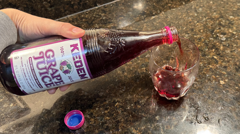 Pouring grape juice into glass on countertop