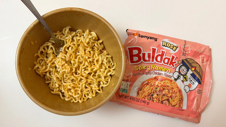 Bowl of Buldak Rosé noodles and its original packaging on white surface
