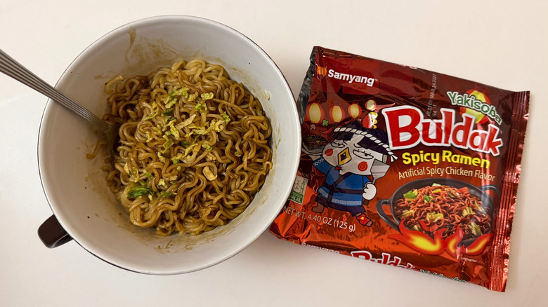 Bowl of Buldak Yakisoba noodles next to its original packaging on white surface