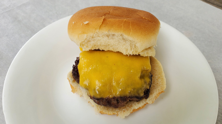 A beef slider with American cheese on a white plate