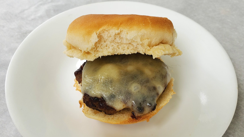 A beef slider with white cheddar on a white plate