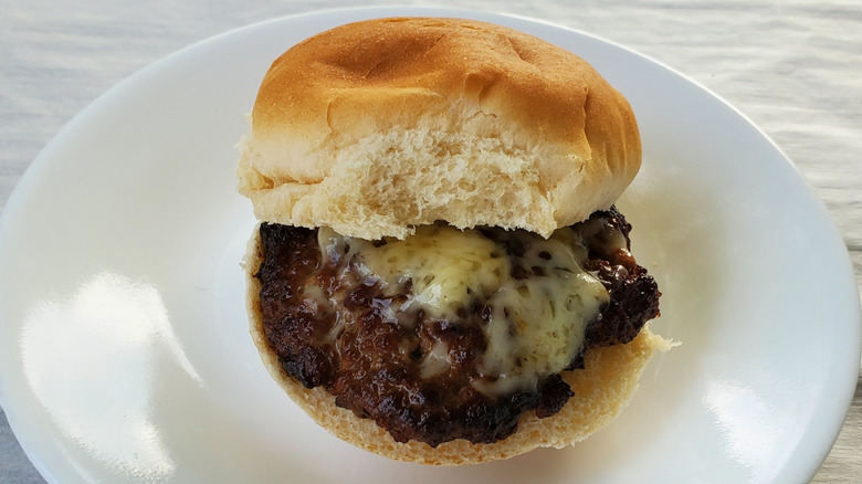 A beef slider with Jarlsberg cheese on a white plate
