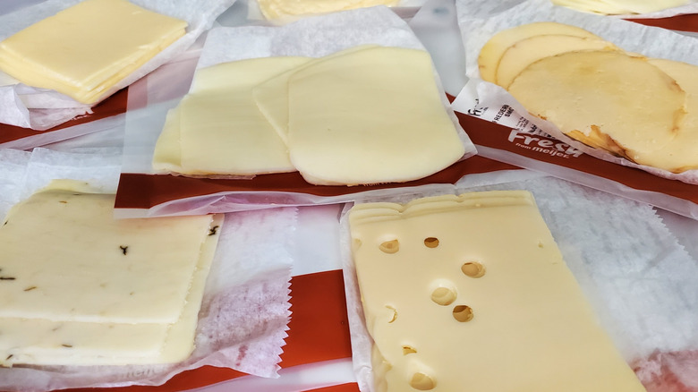 Assorted sliced deli cheeses laid out on parchment paper
