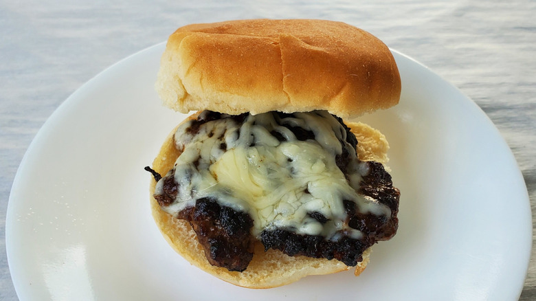 A beef slider with Monterey jack cheese on a white plate