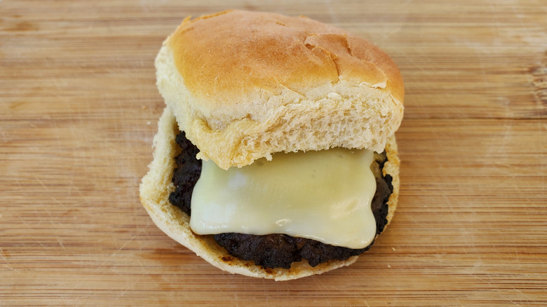 A beef slider with mozzarella on a wooden board