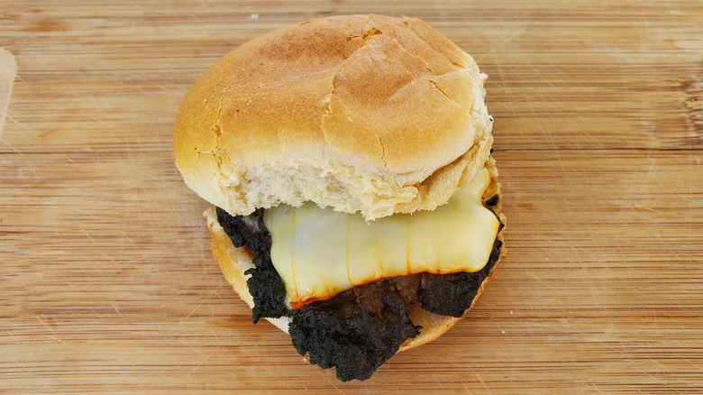 A beef slider with Muenster cheese on a wooden board