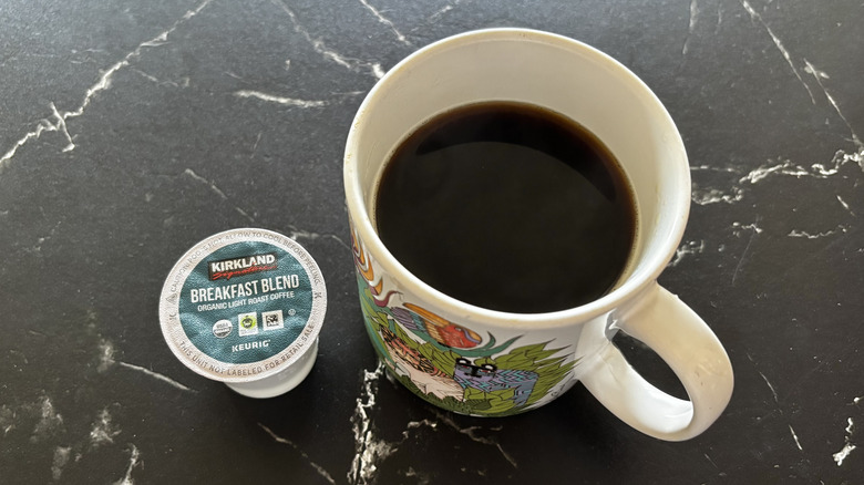 Kirkland Breakfast Blend coffee pod next to brewed cup of coffee