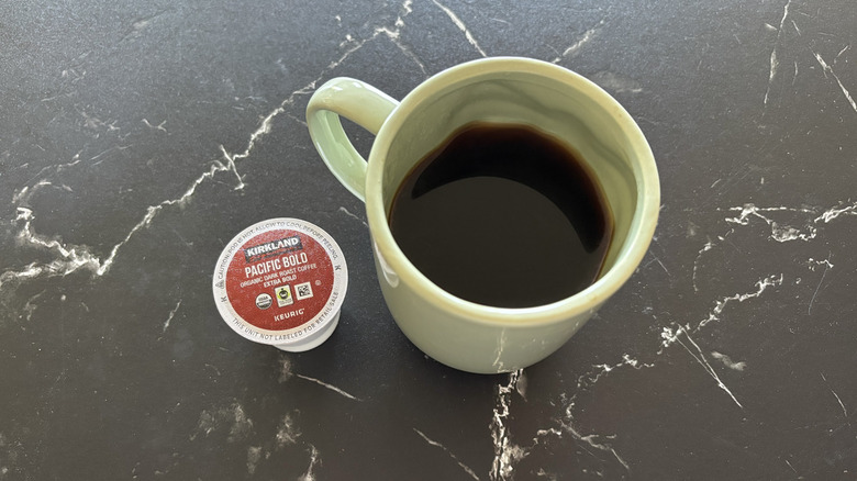 Kirkland Pacific Bold coffee pod next to brewed cup of coffee