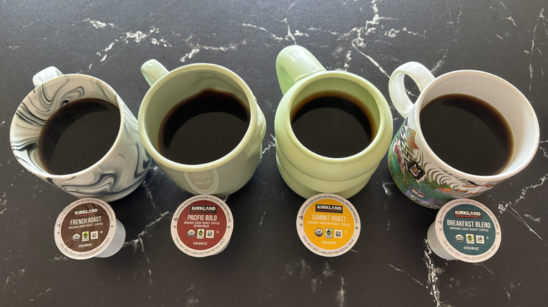Four brewed cups of coffee with various Kirkland coffee pods in front