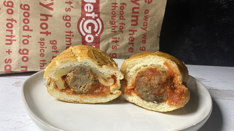 A GetGo meatball sub cut in half on a plate in front of the to-go packaging
