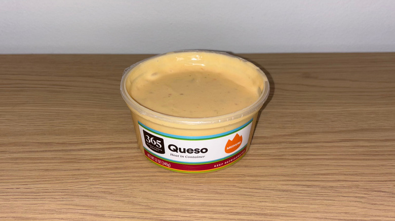 Container of Whole Foods 365 Queso on a wood table.