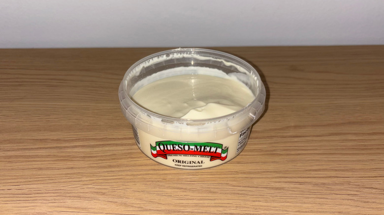 Container of Original Queso-Melt on a wood table.