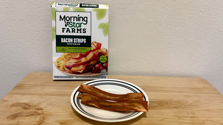 A plate of prepared MorningStar Farms Bacon in front of its packaging