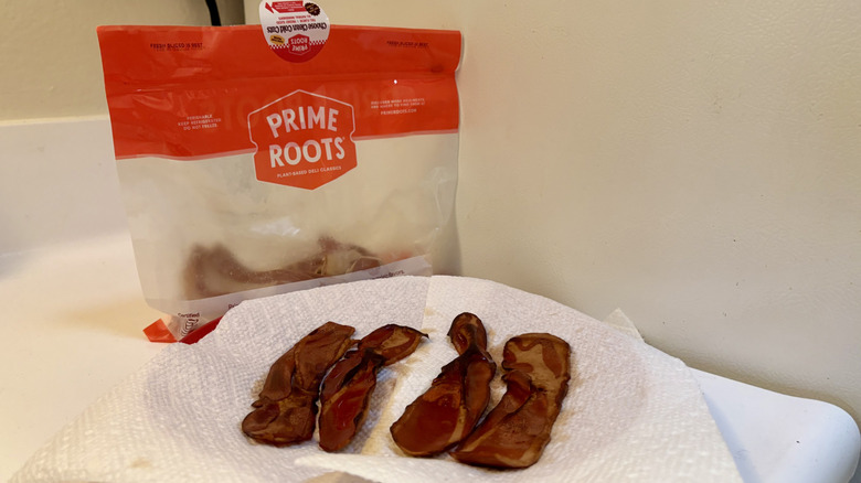 A plate of prepared Prime Roots Bacon in front of its packaging
