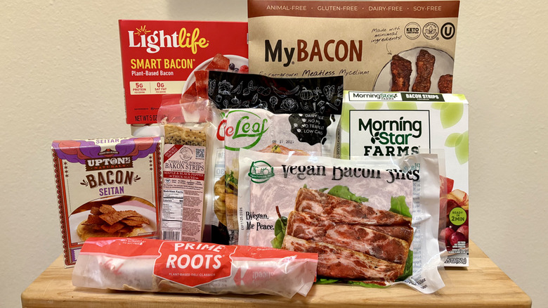A group of plant-based bacon brands arranged on wooden table