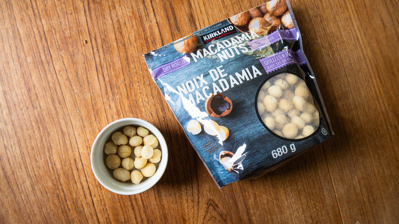 A bag of Kirkland Dry Roasted Macadamia Nuts with Sea Salt beside a ramekin with nuts.