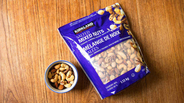 A bag of Kirkland Signature Salted Mixed Nuts beside a ramekin with nuts.