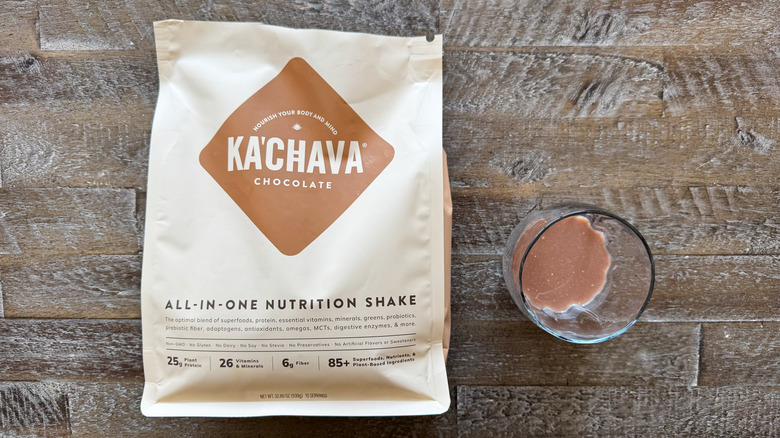 package and cup of Ka'Chava Chocolate Nutrition Shake mix on wooden surface