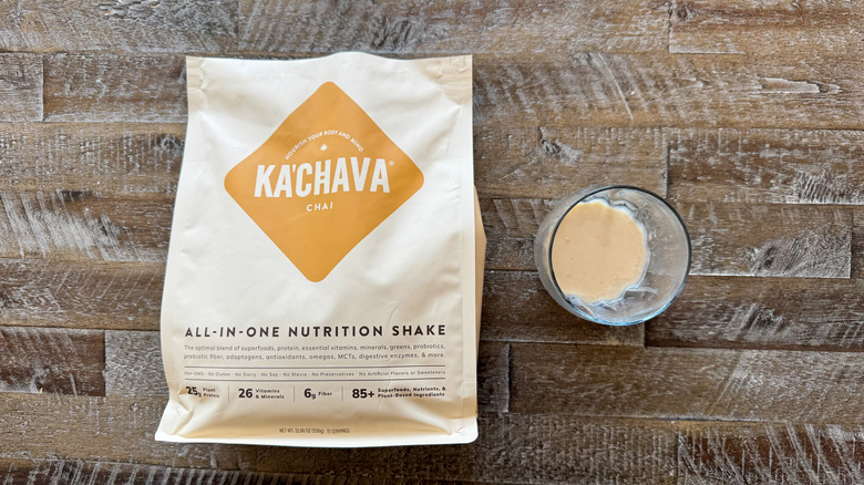 package and cup of Ka'Chava Chai Nutrition Shake mix on wooden surface