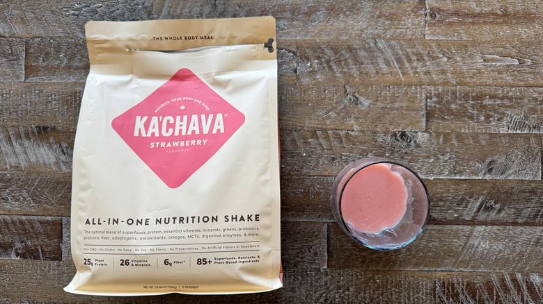 package and cup of Ka'Chava Strawberry Nutrition Shake mix on wooden surface