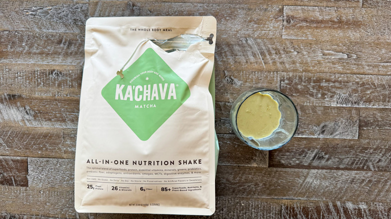 package and cup of Ka'Chava Matcha Nutrition Shake mix on wooden surface