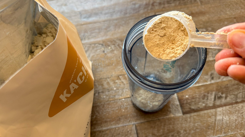 Scooping Ka'Chava Nutrition Shake mix into a blender bottle