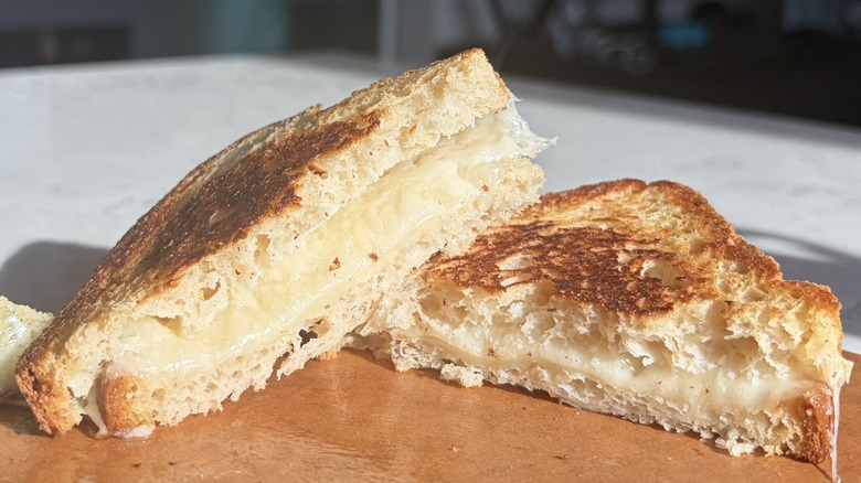 A halved grilled cheese sandwich made with Baby Swiss cheese sits on a cutting board