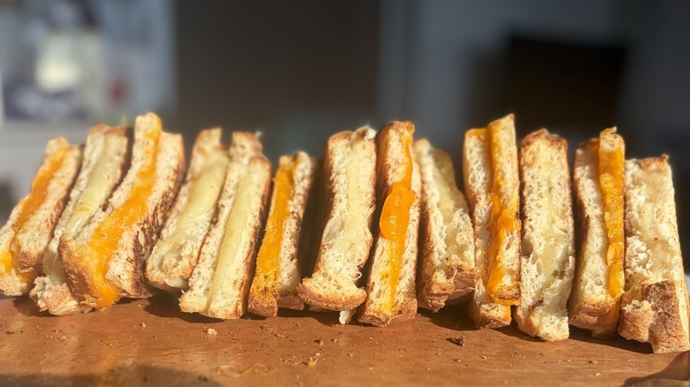 Grilled cheese sandwiches made with various cheeses sit in a line
