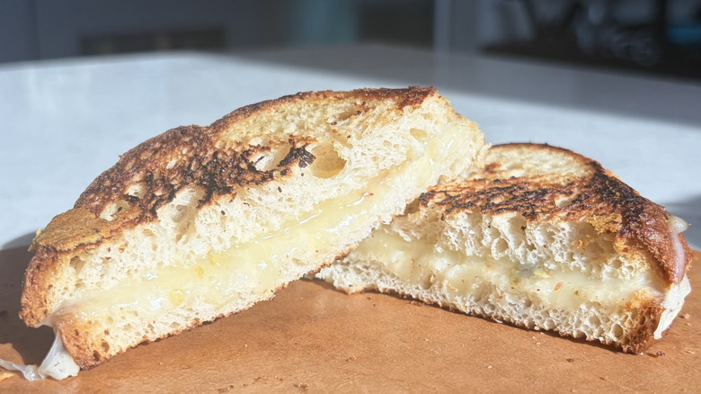 A halved grilled cheese sandwich made with pepper Jack cheese sits on a cutting board